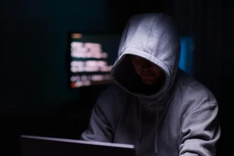 Hacker using the computer. Man in a hoodie breaks the access to steal Stock Photos