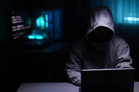 Hacker using the computer. Man in a hoodie breaks the access to steal 스톡 사진