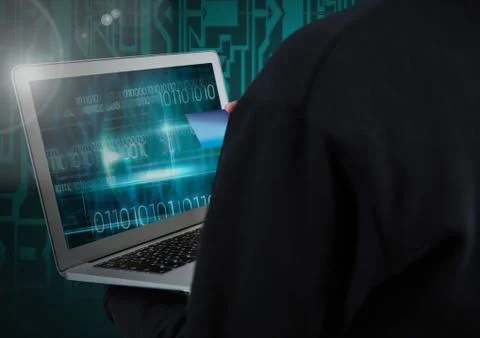 Hacker using a laptop and holding a credit card in front of digital background 스톡 사진