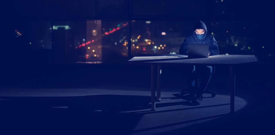 Hacker using laptop computer while working in dark office Foto stock