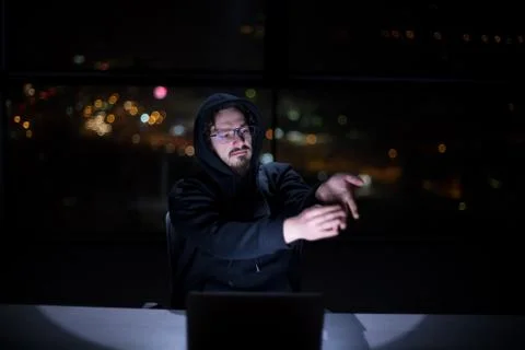 Hacker using laptop computer while working in dark office 스톡 사진