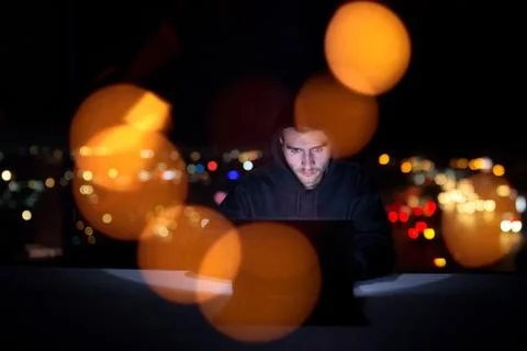 Hacker using laptop computer while working in dark office Foto stock