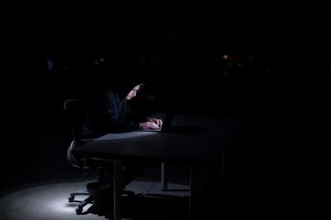 Hacker using laptop computer while working in dark office 스톡 사진