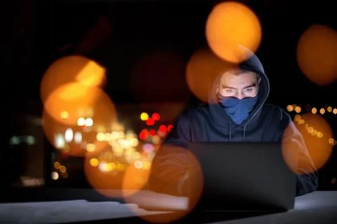 Hacker using laptop computer while working in dark office Foto stock