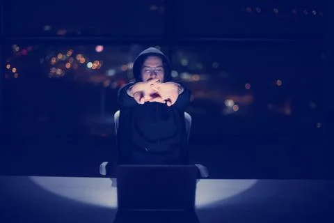 Hacker using laptop computer while working in dark office Foto stock