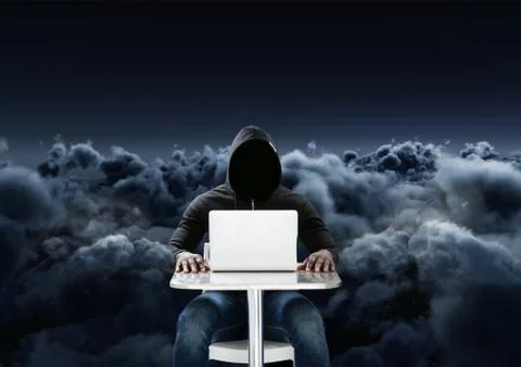 Hacker using a laptop in front of 3d cloudy black background Stock Photos