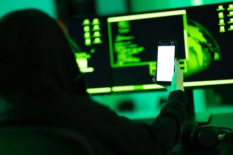 Hacker using smartphone in dimly lit cyber security environment Stock Photos