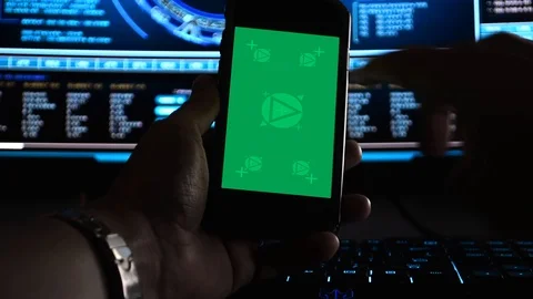 Hacker using a smartphone in front of hi-tech screens, motion-tracked for Stock Footage 107589149
