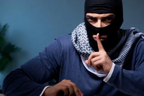 Hacker wearing balaclava mask hacking computer Stock Photos