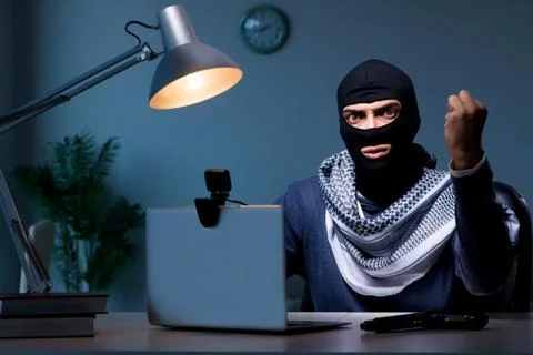 Hacker wearing balaclava mask hacking computer Stock Photos