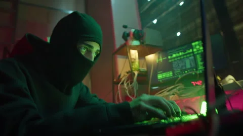Hacker wearing balaclava stealing information from laptop, breaking password and Stock Footage 158394204