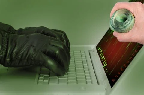 Hacker wearing black gloves using a laptop activating an attack using ransomw Stock Photos