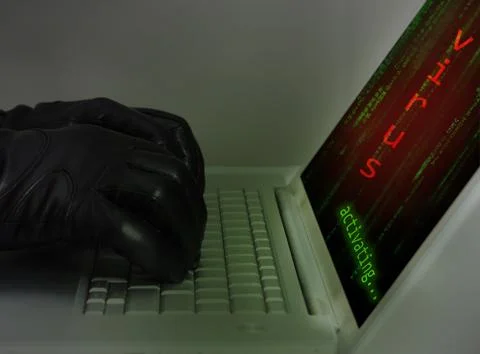 Hacker wearing black gloves using a laptop injecting a virus 스톡 사진