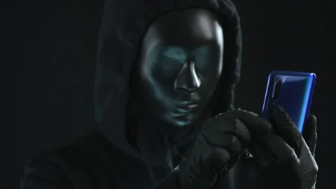 Hacker wearing black mask pulls INFORMATION tab from a smartphone. Hacking Stock Footage 138279711