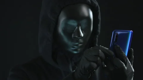 Hacker wearing black mask pulls IDENTITY tab from a smartphone Stock Footage 139966720