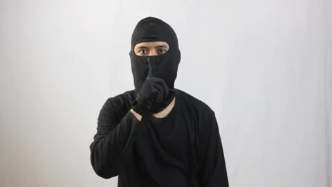 Hacker wearing black suit and black mask gesturing silence sign Stock Footage 319411689