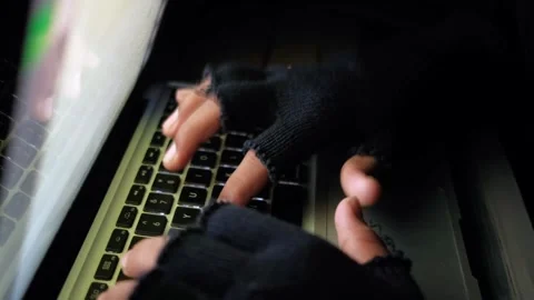 Hacker wearing fingerless gloves typing fast on laptop in dark room represe.. Stock Footage 333031546