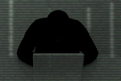 Hacker wearing a hooded top using laptop computer in the dark. The man breaks 스톡 사진