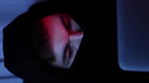 Hacker wearing hoodie programming on laptop. Coding on screen. Vertical video Stock Footage 255252215