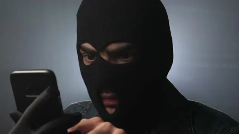 Hacker Wearing a Mask Hacking a Cell Phone 库存影片 148755907