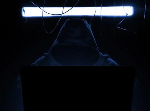 Hacker at work in the blue gloomy lighting. 库存照片