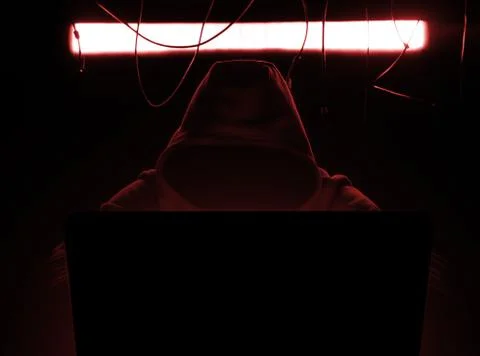 Hacker at work in the red gloomy lighting. Stock Photos