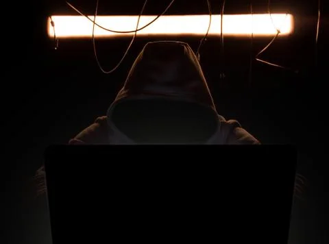 Hacker at work in the yellow gloomy lighting. Stock Photos