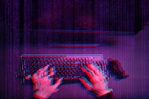 Hacker working with computer in dark room with digital interface around. Image Stock Photos