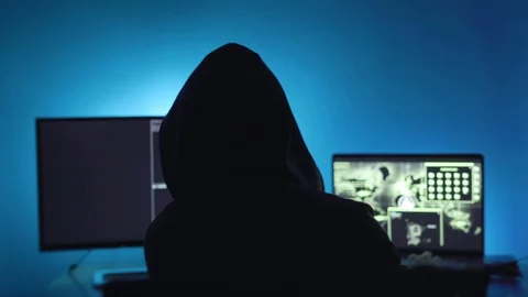 Hacker working on a computer Hooded hacker coding on computer in dark room. Stock Footage 127734204