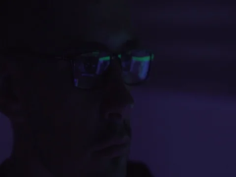 Hacker working on a computer while green code characters reflect on his glasses Stock Footage 81061349