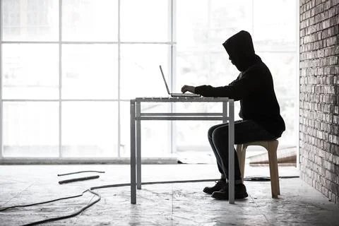 Hacker working in hideaway place and using labtop, concept for computer crime Stock Photos