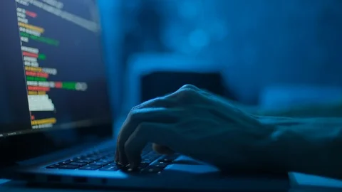 Hacker is working on laptop at night. Hands are typing a virus code at keyboard Stock Footage 121588755