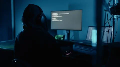 Hacker working on laptop at night in modern workspace. Hacker or cyber criminal. 写真素材