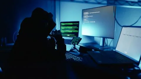 Hacker working on laptop at night in modern workspace. Hacker or cyber criminal. Stock Photos