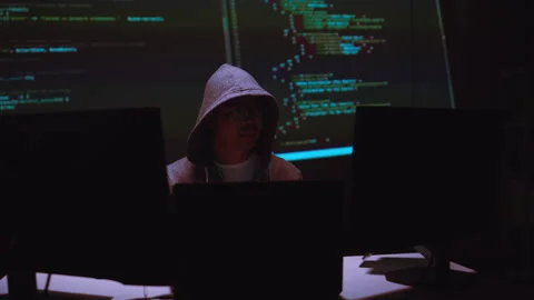 Hacker Working with Multiple Computer Screens Displaying Code in a Dark Setti Stock Footage 336678510