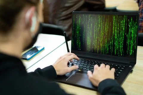 Hacker writes code on laptop in matrix style Stock Photos