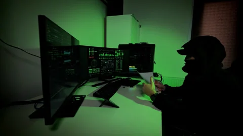 Hacker writes notes on paper then rips them nervously beside glowing computer Stockbeeldmateriaal 316733735