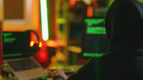 Hacker writing code cracking computer. Man programmer in hoodie cracks system Stock Footage 272910185