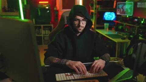 Hacker writing code cracking computer. Man programmer in hoodie cracks system Stock Footage 273512086
