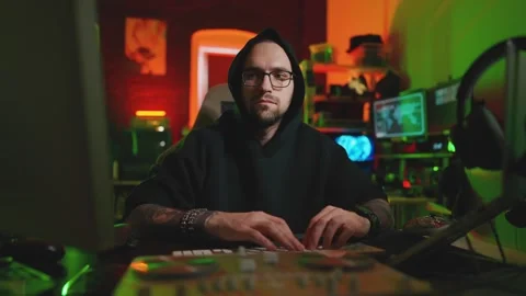 Hacker writing code cracking computer. Man programmer in hoodie cracks system Stock Footage 273512216