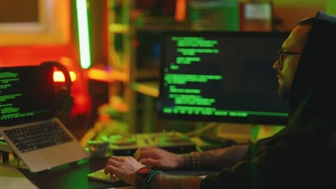 Hacker writing code cracking computer. Man programmer in hoodie cracks system Stock Footage 273512260