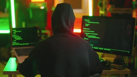 Hacker writing code cracking computer. Man programmer in hoodie cracks system Stock Footage 273512413