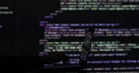 Hacker writing code cracking computer. Programming code in the background 写真素材