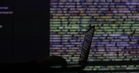 Hacker writing code cracking computer. Programming code in the background Stock Photos