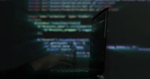 Hacker writing code cracking computer. Programming code in the background Stock Photos