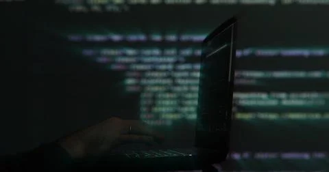 Hacker writing code cracking computer. Programming code in the background 写真素材