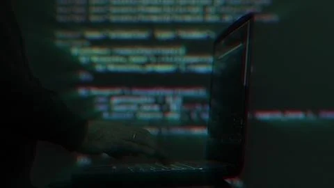 Hacker writing code cracking computer. Programming code in the background 写真素材