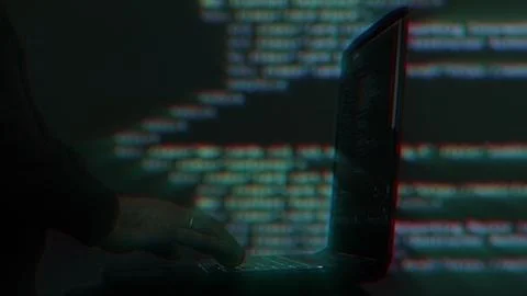 Hacker writing code cracking computer. Programming code in the background Stock Photos