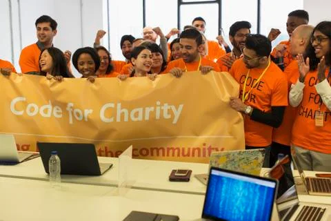 Hackers with banner cheering, coding for charity at hackathon Stock Photos