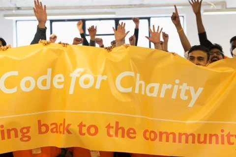 Hackers with banner cheering, coding for charity at hackathon Stock Photos